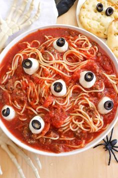 a bowl of spaghetti with googly eyes on it and crackers in the background