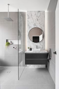 a modern bathroom with marble walls and flooring, including a large mirror above the sink