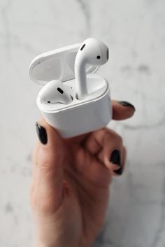 a person holding an airpods in their hand