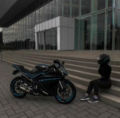 a person sitting on the steps next to a parked motorcycle and another person standing in front of some stairs