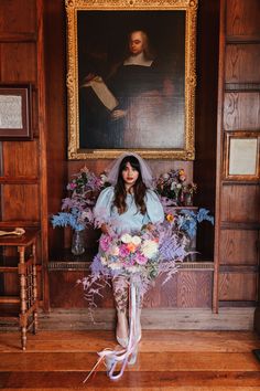 a woman holding a bouquet of flowers in front of a painting on a wooden wall