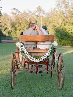 a bride and groom are riding in an old fashioned horse drawn carriage on the grass