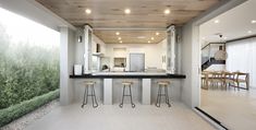 an open concept kitchen and dining area with white walls, wood ceilinging and bar stools