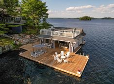 a houseboat is docked on the water with chairs and tables in front of it