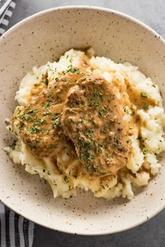 a bowl filled with mashed potatoes covered in gravy and garnished with parsley