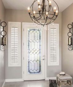 an entryway with a chandelier and white shuttered glass doors in the background