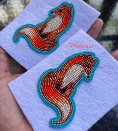 two handmade brooches that have been made to look like fish on them