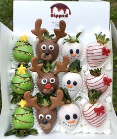 a box filled with chocolate covered strawberries decorated like reindeers and snowmen,