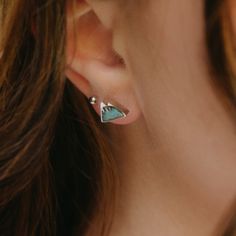 a close up of a woman's ear with a triangle shaped stud on it