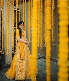 a woman standing in front of some yellow garlands and looking at her cell phone