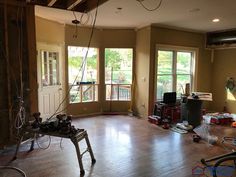 an empty room with hard wood flooring and construction equipment on the ground in front of large windows