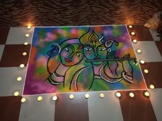 a colorful painting on the floor with lights around it and two people holding a flute