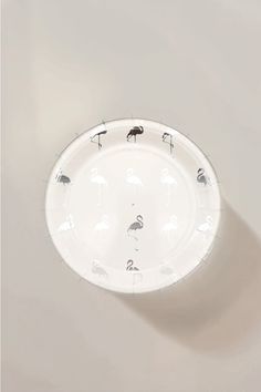 a paper plate with black and white flamingos on the rim, hanging from a wall