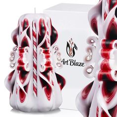 an artisticly designed vase sitting in front of a white box with red and black designs on it