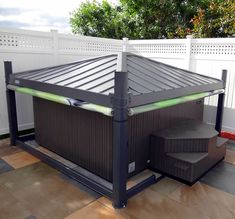 a hot tub sitting on top of a wooden floor next to a white picket fence