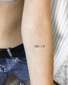 a woman's arm with the word smile tattooed on it