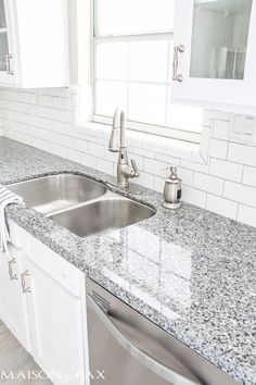 a kitchen with marble counter tops and white cabinets