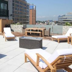 an outdoor patio with lounge chairs and fire pit in the middle of it, surrounded by tall buildings