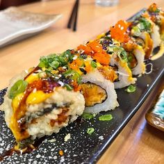 a sushi roll with various toppings on a black plate