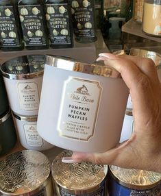 a person holding up a candle in front of some other candles on display at a store