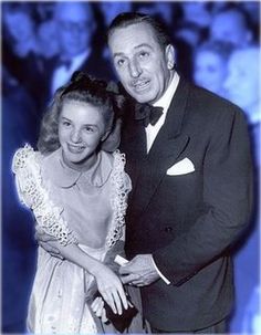 a man in a tuxedo standing next to a woman