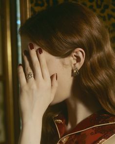 a woman with red nails holding her hand to her face