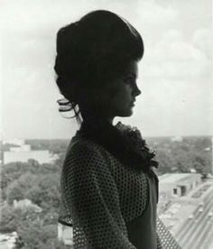 a black and white photo of a woman standing in front of a cityscape