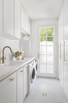 a washer and dryer in a white laundry room with gold handles on the doors