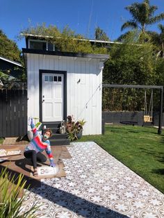 a person on a skateboard in front of a small house with grass and trees