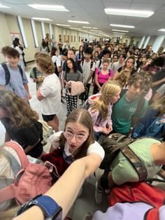 a group of people standing around each other in a room with many backpacks on the floor