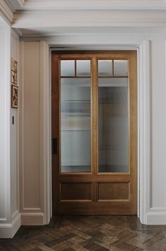 an empty room with a wooden door and white walls, wood flooring and parqueted floors