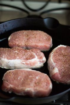 four raw meats are cooking in a skillet