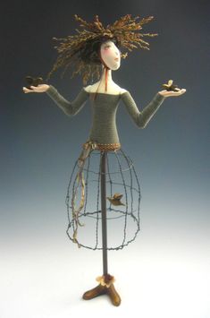 a wire mannequin holding two hands in front of her face and standing on one leg