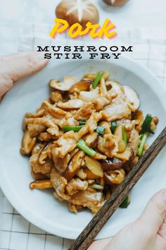 someone holding chopsticks in front of a plate of food with mushrooms and stir fry