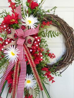 a red and white wreath with ladybugs, daisies and flowers on the front door