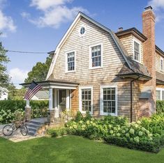 a bike is parked in front of a house with a flag on the porch and bushes around it