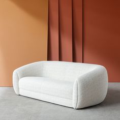 a white couch sitting in front of a wall with red and orange walls behind it