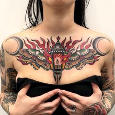 a woman with tattoos on her chest is holding her hands in front of her stomach