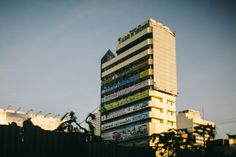 a tall white building with lots of stickers on it's side and trees in the foreground