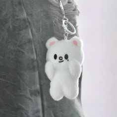 a white bear keychain hanging from the side of a person's shirt