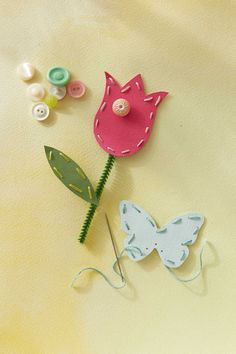 a paper flower and some buttons on a yellow surface with white fabric behind the flowers