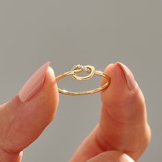 a woman's hand holding a gold ring with two diamonds