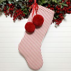 a red and white striped christmas stocking with two pom - poms hanging from it