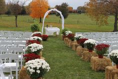 an outdoor wedding setup with hay bales and red and white flowers in vases