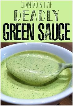 a white bowl filled with green sauce on top of a wooden table next to a spoon