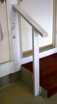 a white stair case next to a red carpeted floor