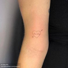 a woman's arm with a small heart tattoo on the left side of her arm