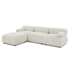 a white sectional couch with two pillows on it's back and one end facing the camera