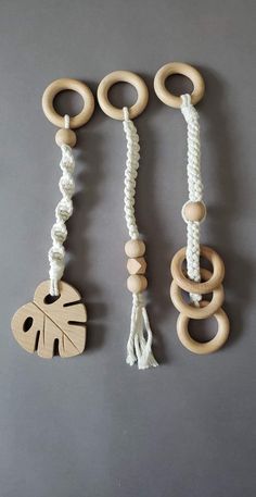 three wooden toys are hanging on a gray wall, one is made out of rope and the other has an elephant's head