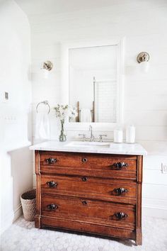 a bathroom vanity with two drawers and a large mirror above it in a white room